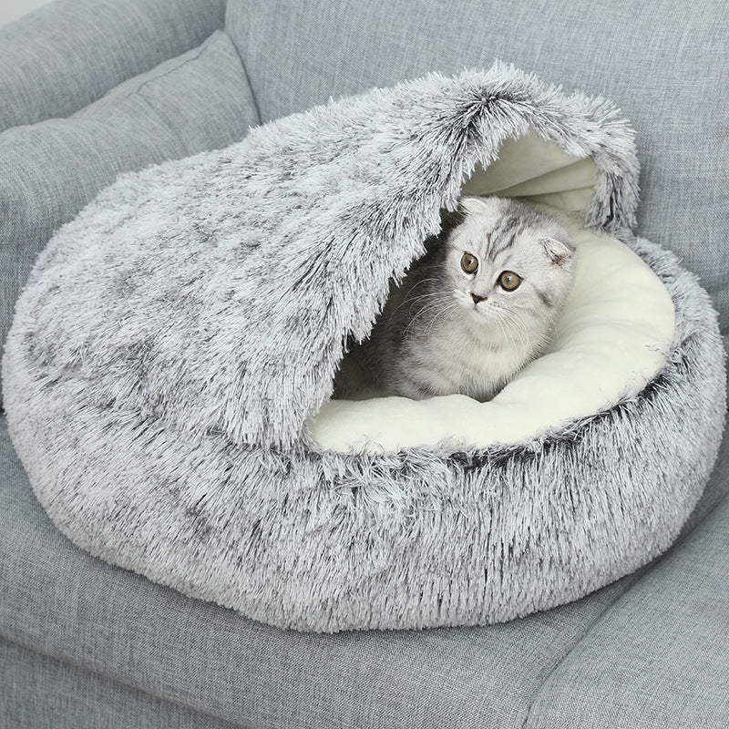 Cat lying inside a fluffy gray pet bed on a gray couch.