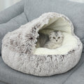 Cat lying inside a plush, gray pet cave on a gray couch.