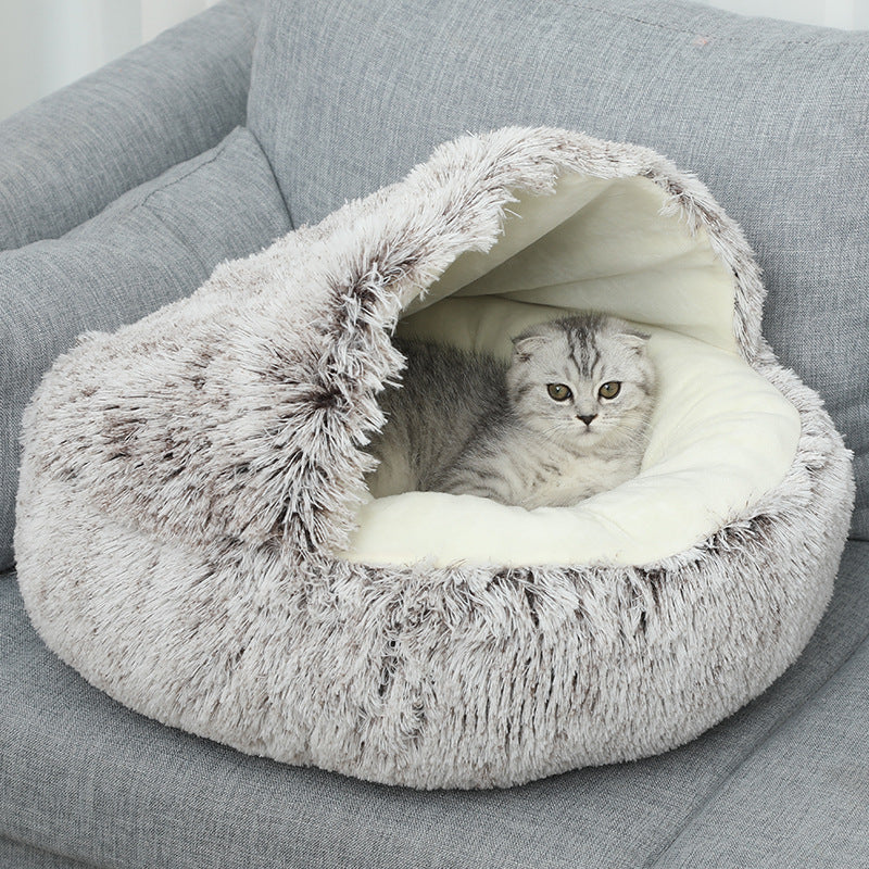 Cat lying inside a plush, gray pet cave on a gray couch.