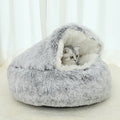 Cat lying inside a fluffy gray pet bed on a light background