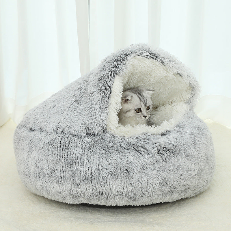 Cat lying inside a fluffy gray pet bed on a light background