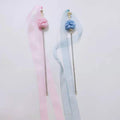 Two pastel-colored hairbands with pom-poms on a light gray background