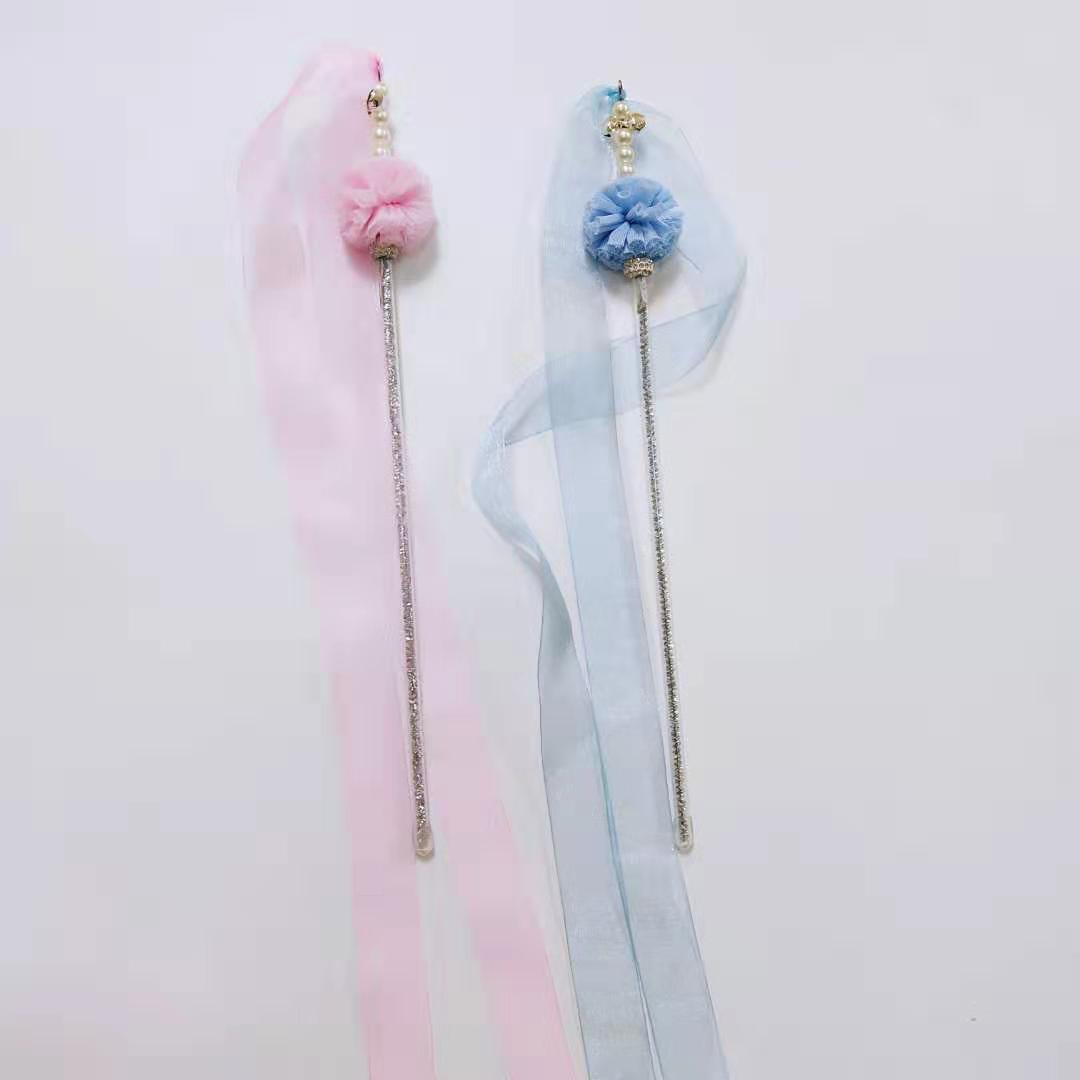 Two pastel-colored hairbands with pom-poms on a light gray background