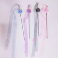 Four decorative hair sticks with ribbons on a light pink background