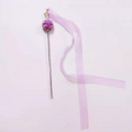 Decorative hair stick with a fluffy purple ball and a long pink ribbon on a light pink background